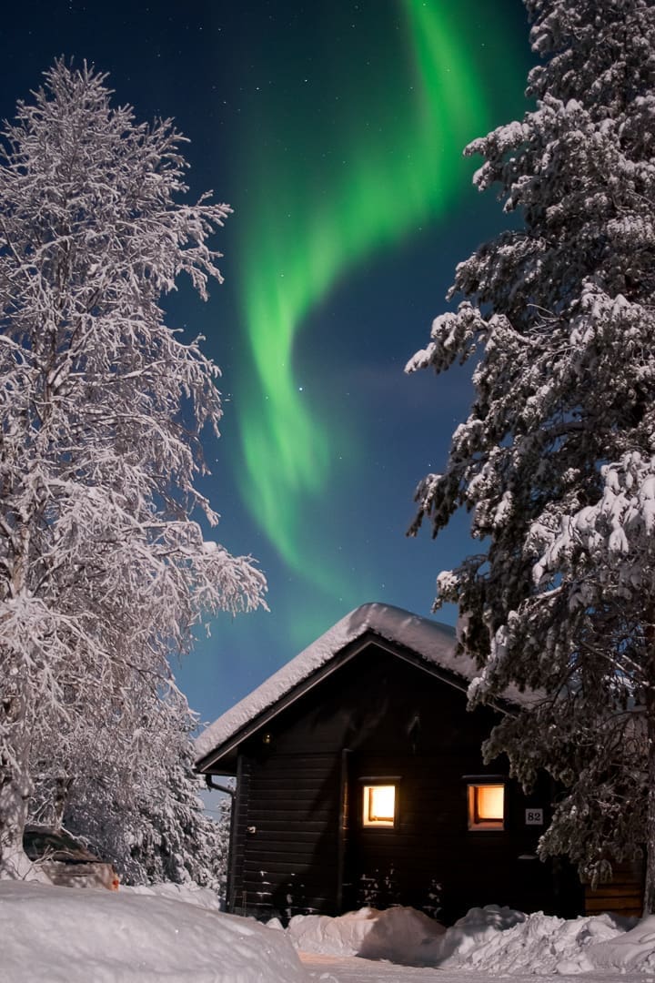 Aurores boréales au-dessus d’une cabane en rondins en Laponie